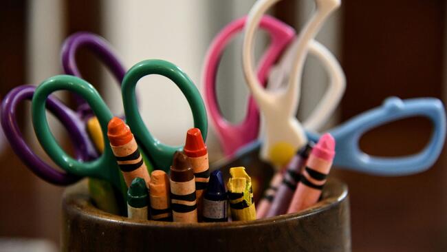 multicolored scissors and crayons in a container