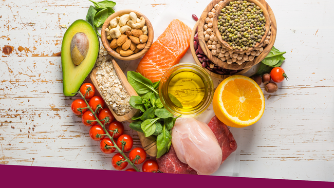 A selection of heart-healthy foods laid out in a shape of a heart on a white wooden table.