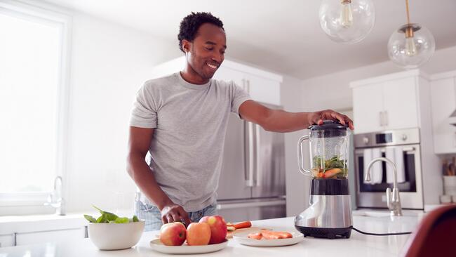 Man blending fruit and vegetables in a blender.