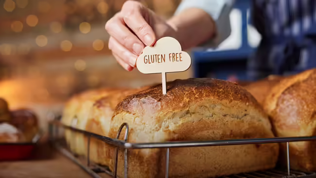 Baked bread on display with a sign going through the bread that reads Gluten Free.