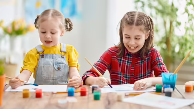 two young girls painting at a table