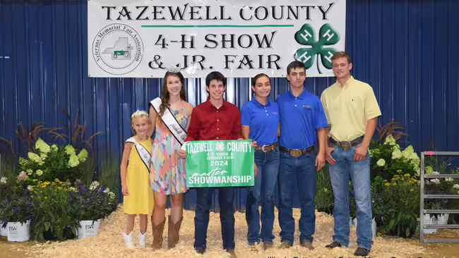 group of people standing in front of 4-H Show banner