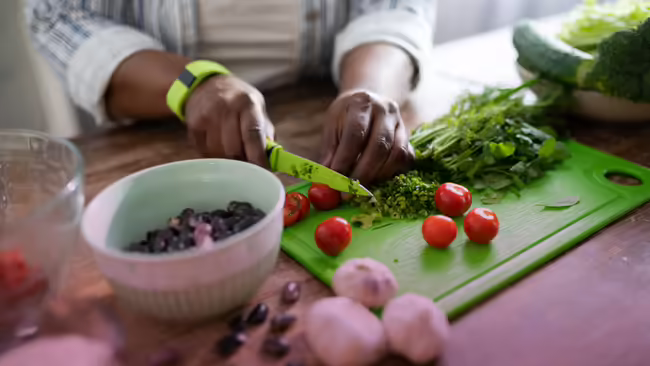 Close up of person's hands cutting vegetables on a cutting board in the ktichen