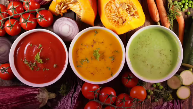 bowls of soup with various vegetables in the background