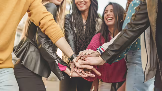 Half circle of people stacking their hands together in a team handstack