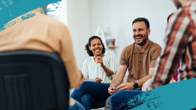 An adult man, looking happy, talking with a group of people