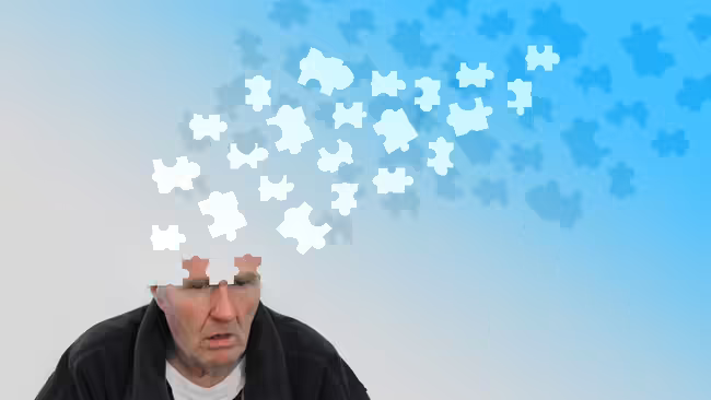 A man sitting looking confused as puzzle pieces float away from his head.