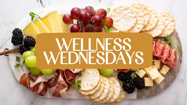 Charcuterie board with fruit, cheese, and crackers overlaid with the text ‘Wellness Wednesdays’ in white on a gold background banner.