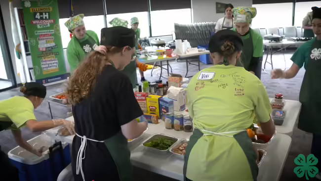 Youth from last year's competition cook on a team at tables. 