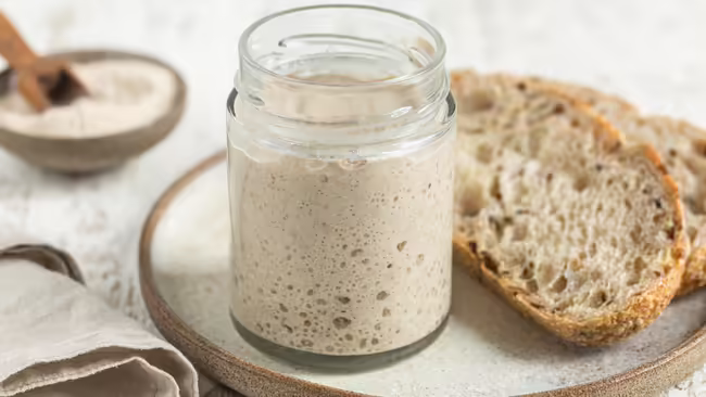 Jar of sourdough and piece of bread on plate