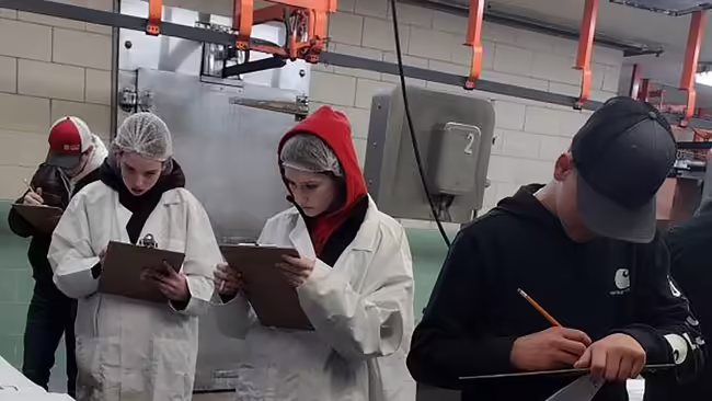 Youth with clipboards evaluate meat cuts.