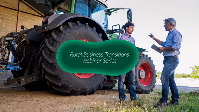 Two men talking in front of a tractor
