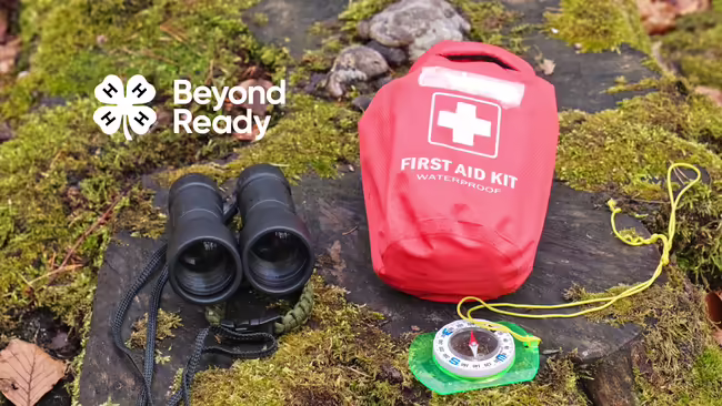 mossy, rocky ground with a compass, first aid kit, and binoculars