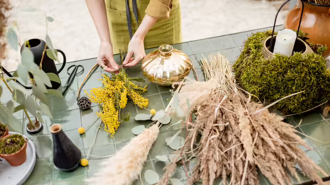 a person making a dried flower arrangement