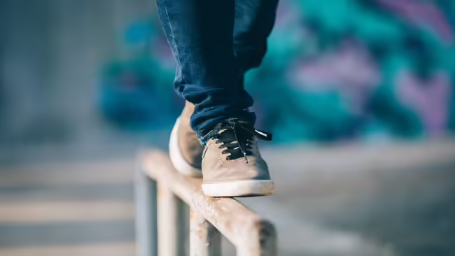 A close up of a person's feet as they balance on a steel bar.