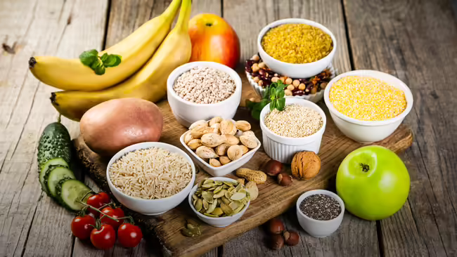 An assortment of healthy carbohydrates arranged on a rustic wooden surface.
