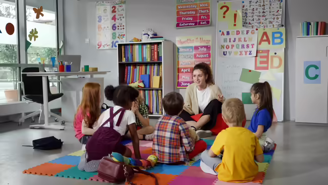 A teacher on the floor with her students 