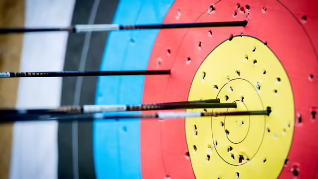 An archery target with metal arrows sticking out of it.