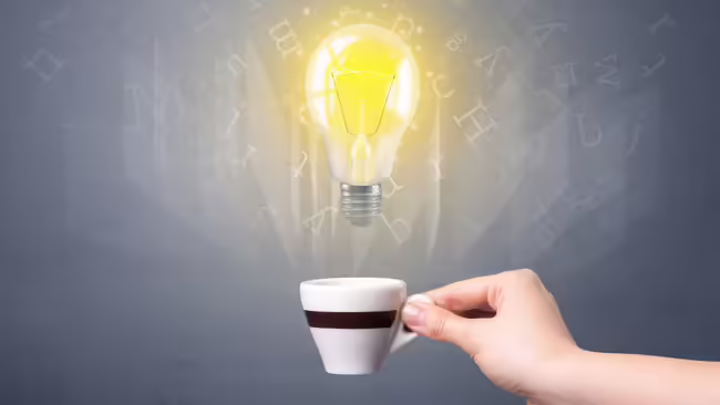 A white coffee mug with a black stripe with a light bulb coming out of the center.