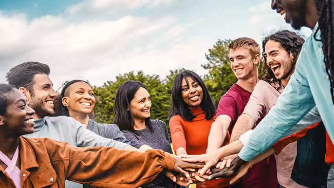 Group of people coming together with their hands in the middle