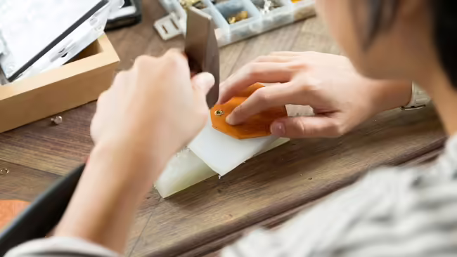 A close-up of a person crafting a small leather good