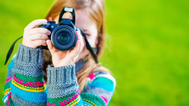 A young girl holding a camera like she's taking a photo