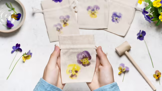 small hands hold a bag that has a flower imprint on it from pounding flower into material.