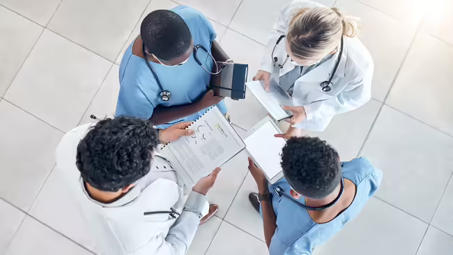 four people wearing medical career clothing, standing in a circle
