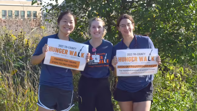 three girls holding Hunger Walk signs