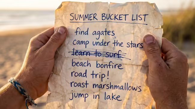 At the beach, a close-up of hands holding a summer bucket list. One item is crossed off.