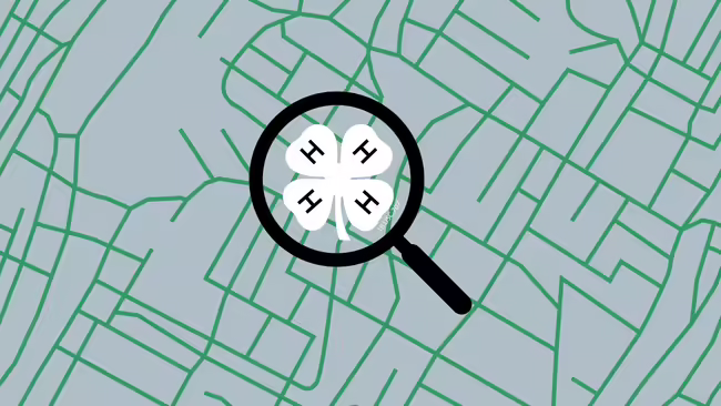 A green map with a magnifying glass with a white 4-H clover inside.