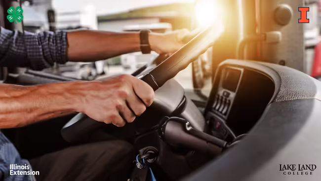 Person driving a vehicle, with hands on the steering wheel. Illinois Extension, 4-H, and Lake Land College logos are visible.