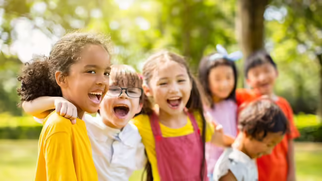 six young kids smiling and standing next to each other outside