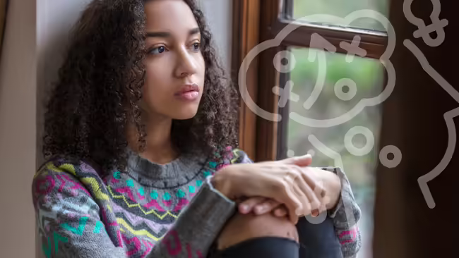 young lady sitting by a wall thinking 
