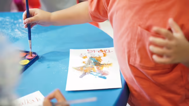 A close-up of a young kid working on a painting/salt art
