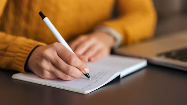 A person using a pen to write in a book.