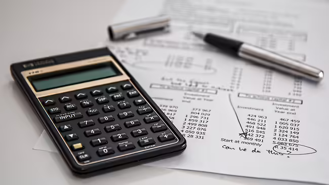 calculator, pen and financial sheet