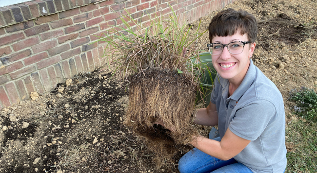 woman holding clump of soil and roots