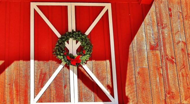 A holiday wreath hangs on red barn doors