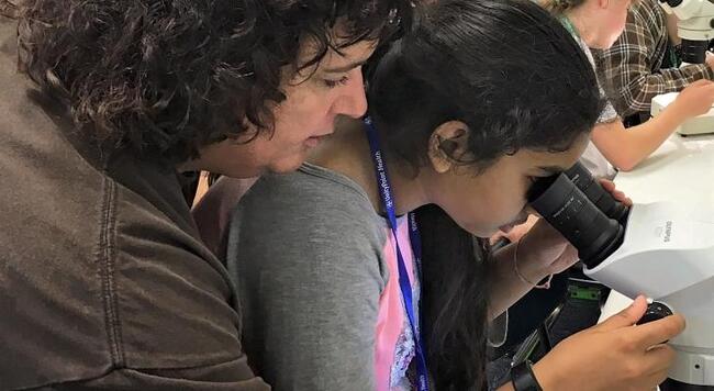 teacher helping girl use a microscope