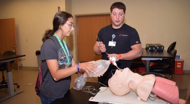 Instructor showing student how to intubate a training mannequin