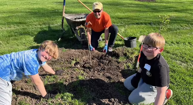 Kids and an adult planting trees