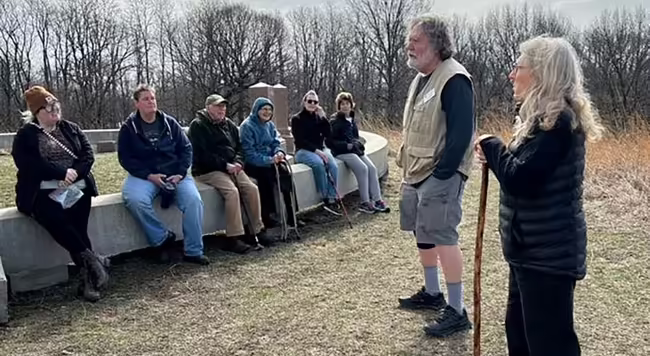 Group of people outdoors, listening to two people standing and talking