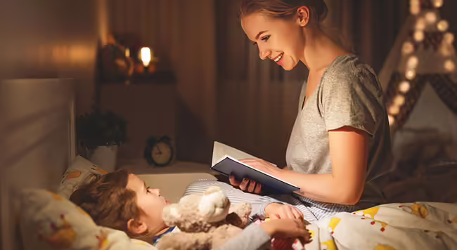 Parent reading a bedtime story to child in bed.