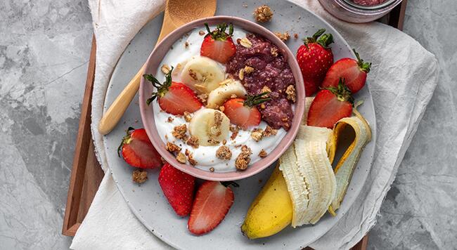 bowl of yogurt and fruit with a banana and strawberries