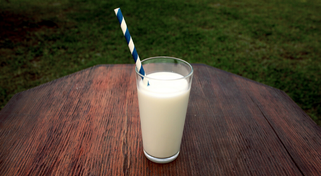 glass of milk with straw set on a picnic table