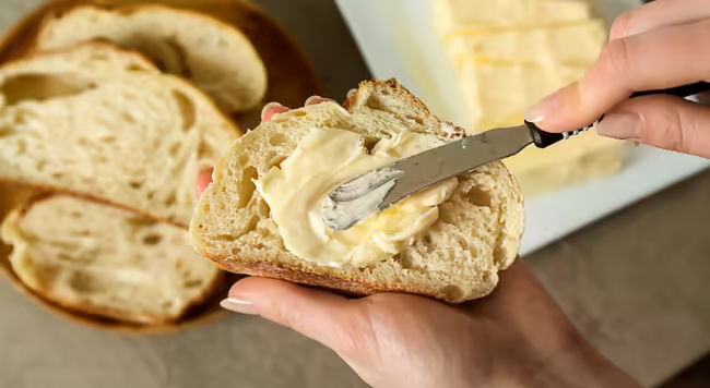 A person spreading butter on toast