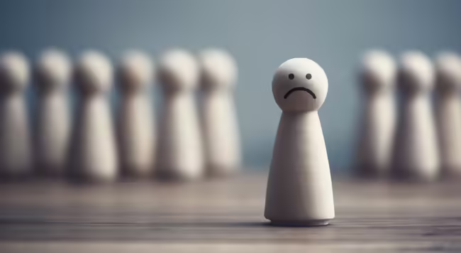 Wooden person with a frown stands in front of a group of wooden people.