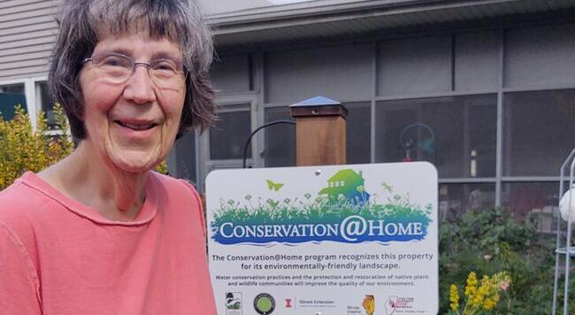 Ellen Denler standing next to her Conservation at Home sign