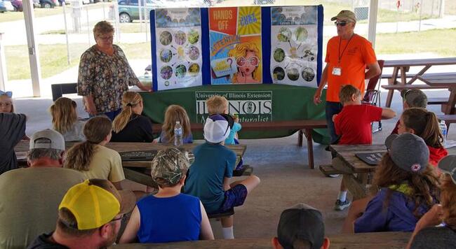 youth sitting on floor while adults present educational material